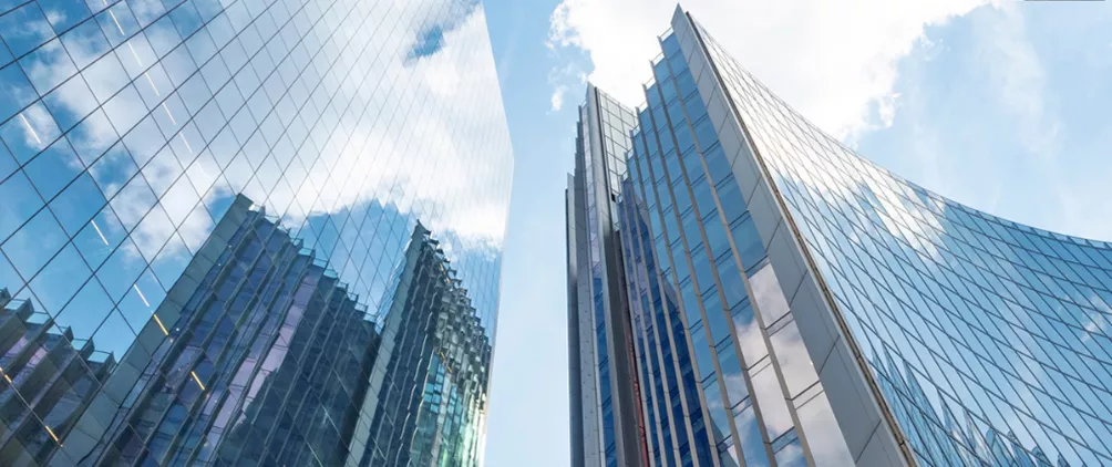 Upward view of modern glass skyscrapers reflecting the sky, showcasing contemporary urban architecture and sleek high-rise building design.
