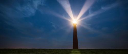 Lighthouse shining beams across a dark sky, representing bright beacons and renewed opportunities for small cap equities.